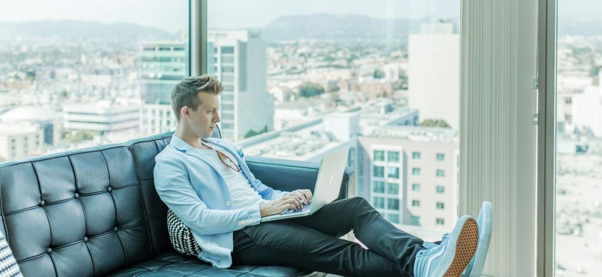 man sitting on sofa while using laptop